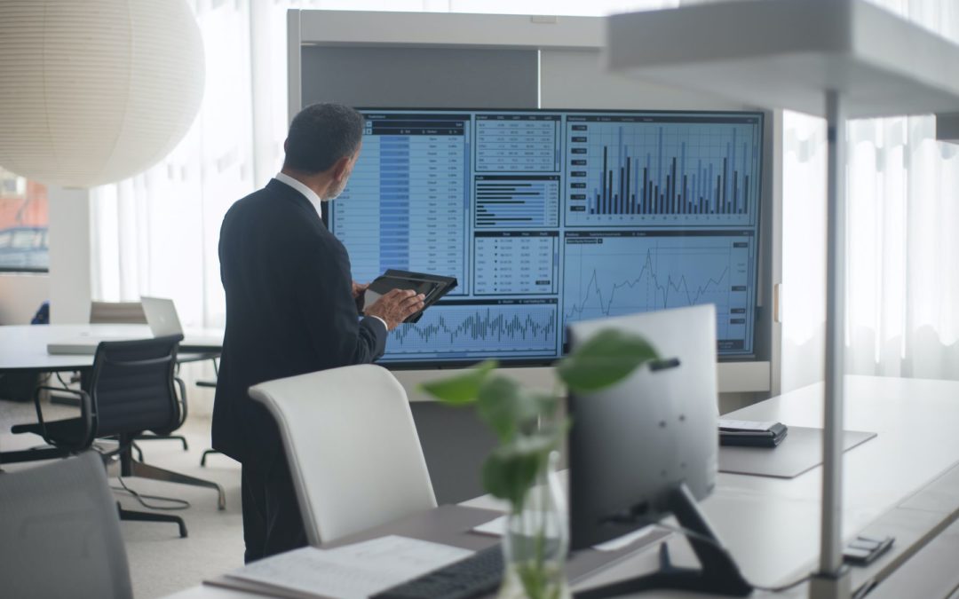 Man standing in front of many computer screens.