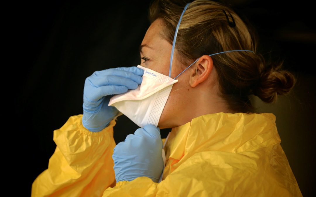 Woman in full protective gown, mask and gloves